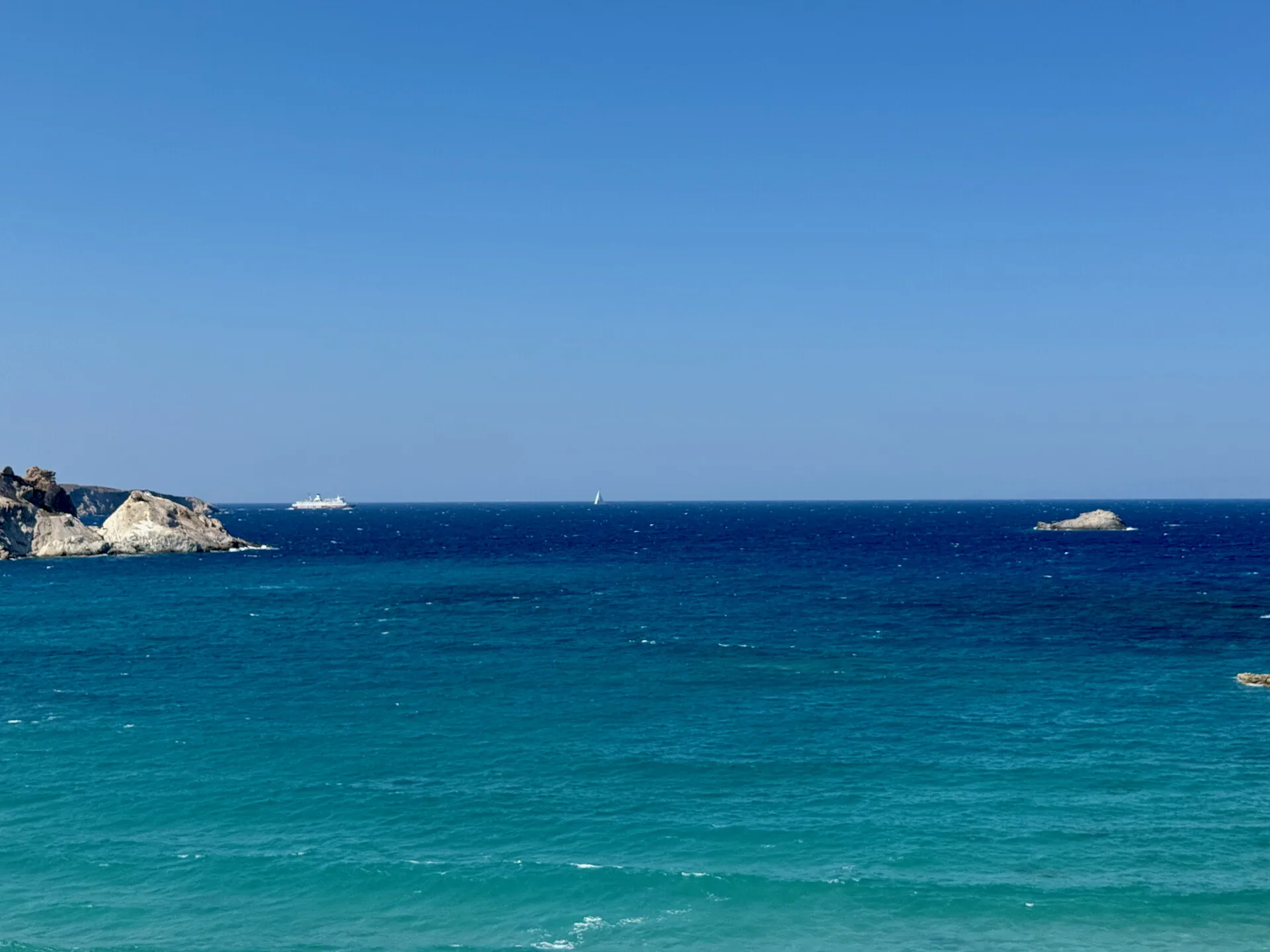 Turquoise sea and a rocky coastline beneath a clear blue sky.