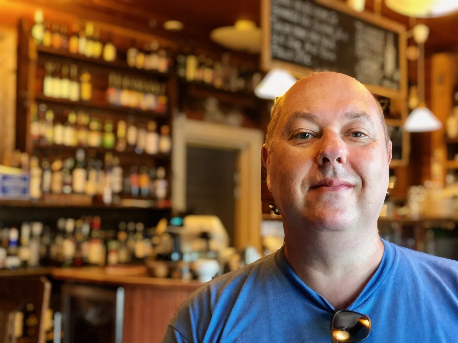 Dave Sag smiling in a blue T-shirt in a warm Finnish bar
